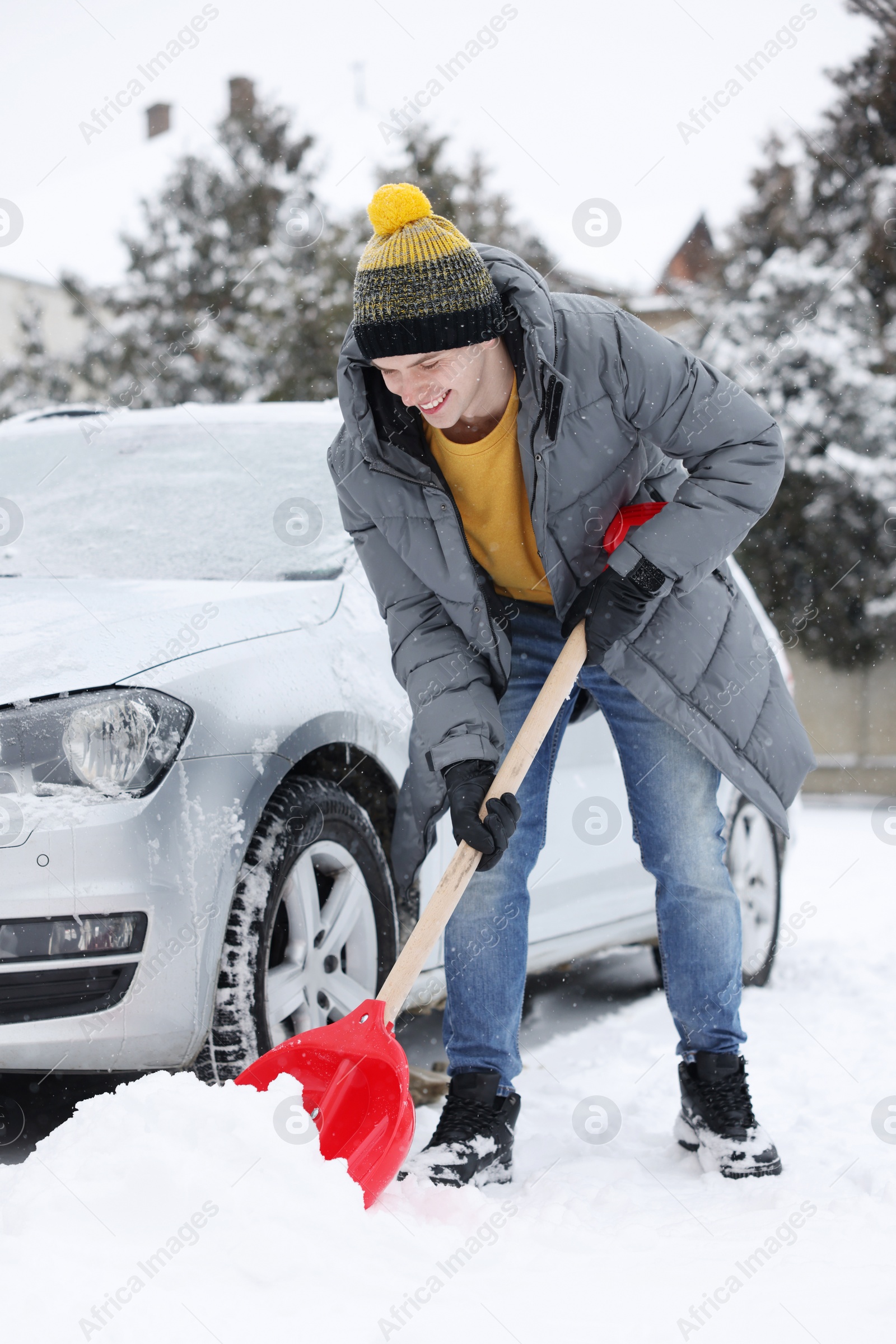 Photo of Man removing snow with shovel near car outdoors