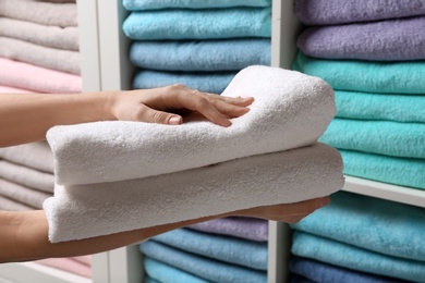 Photo of Woman holding towels near shelf, closeup view