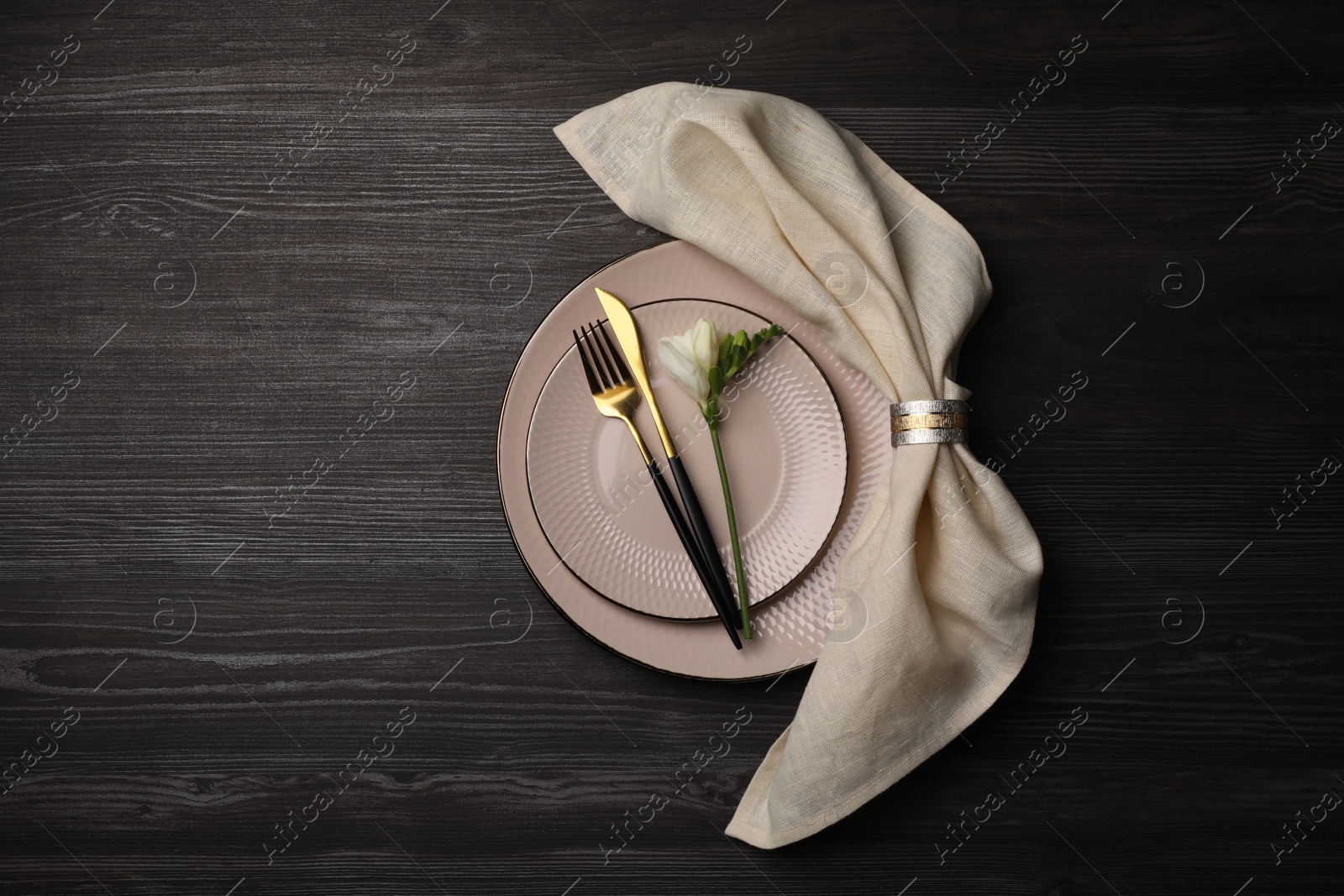 Photo of Stylish table setting. Plates, cutlery, napkin and floral decor on dark wooden background, top view with space for text
