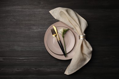 Stylish table setting. Plates, cutlery, napkin and floral decor on dark wooden background, top view with space for text