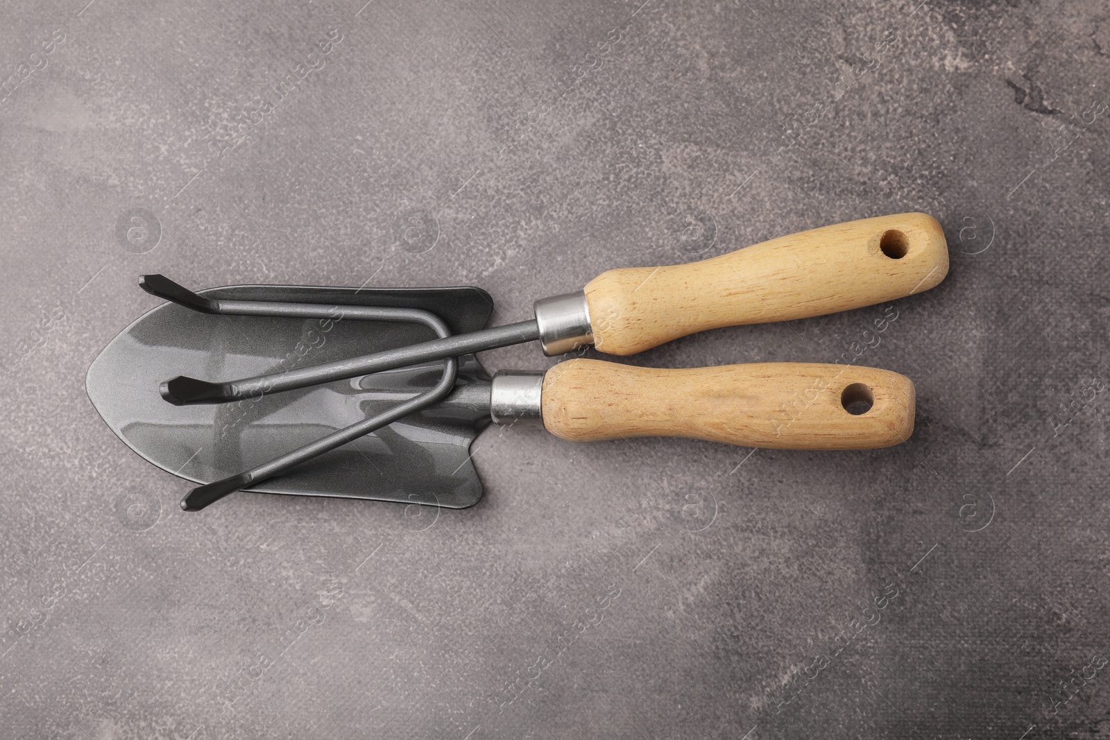 Photo of Gardening trowel and rake on brown textured table, top view