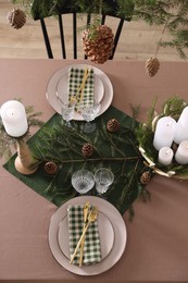 Christmas table setting with burning candles and other festive decor, above view