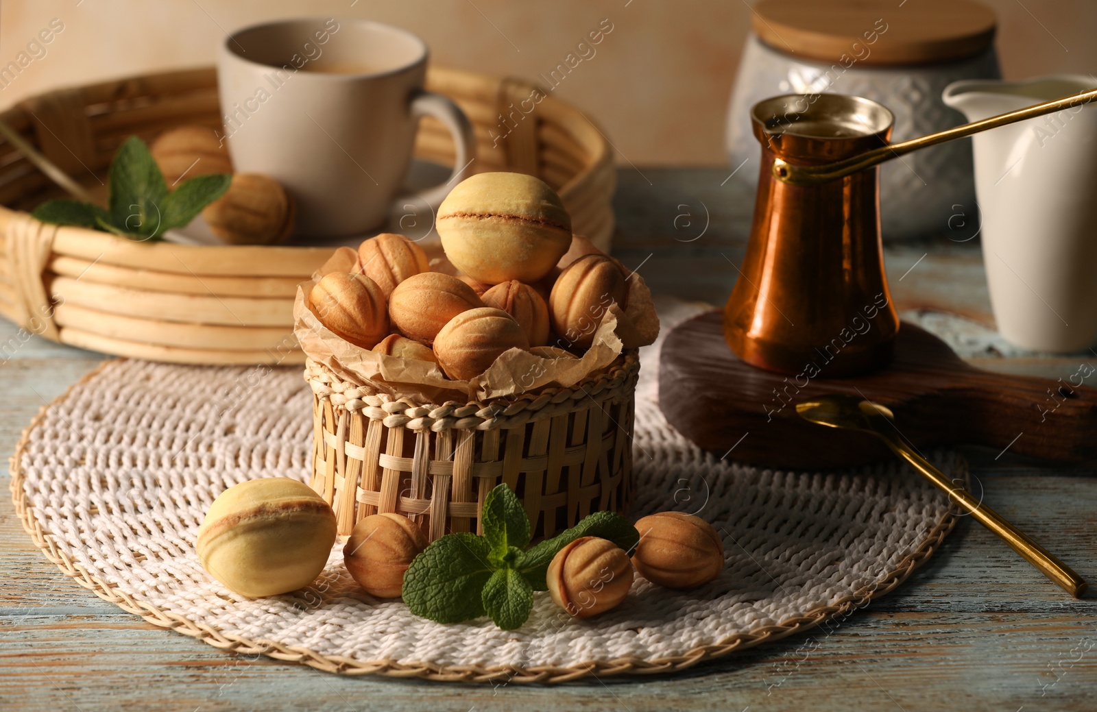 Photo of Aromatic walnut shaped cookies, mint and coffee on table. Homemade pastry filled with caramelized condensed milk