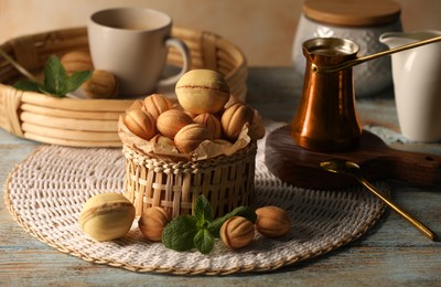 Photo of Aromatic walnut shaped cookies, mint and coffee on table. Homemade pastry filled with caramelized condensed milk