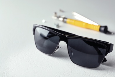 Photo of Stylish sunglasses and fixing tools on white table