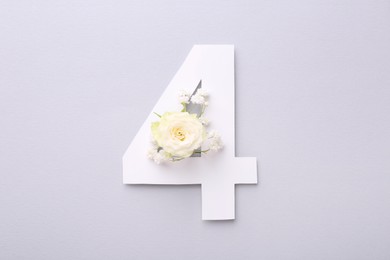 Photo of Paper number 4 and beautiful flowers on light grey background, top view