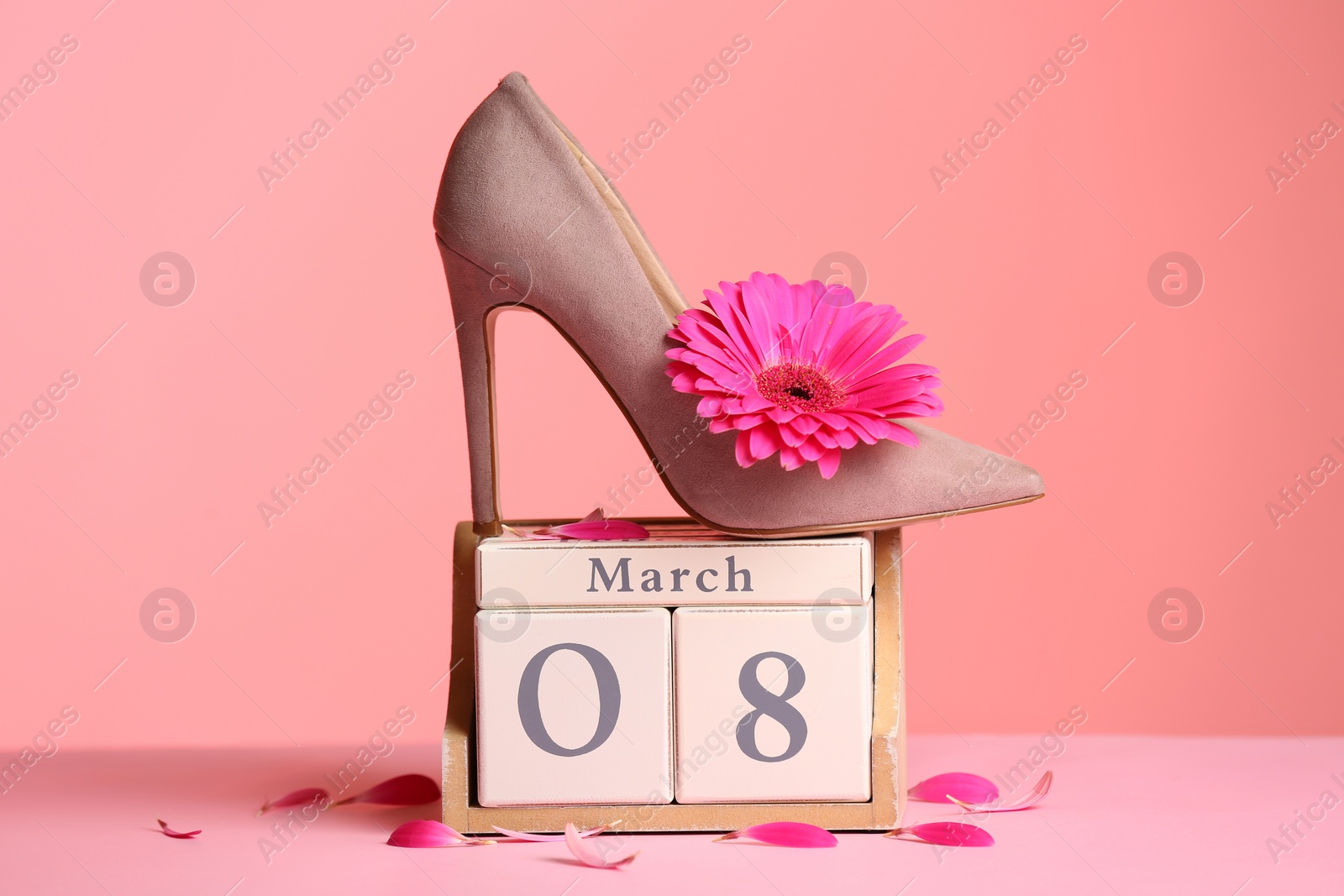 Photo of Stylish lady's shoe, flower and wooden block calendar on table against color background. International Women's Day