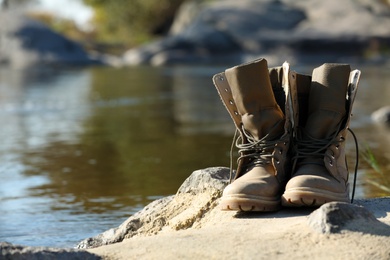Photo of Boots on sand near pond. Space for text