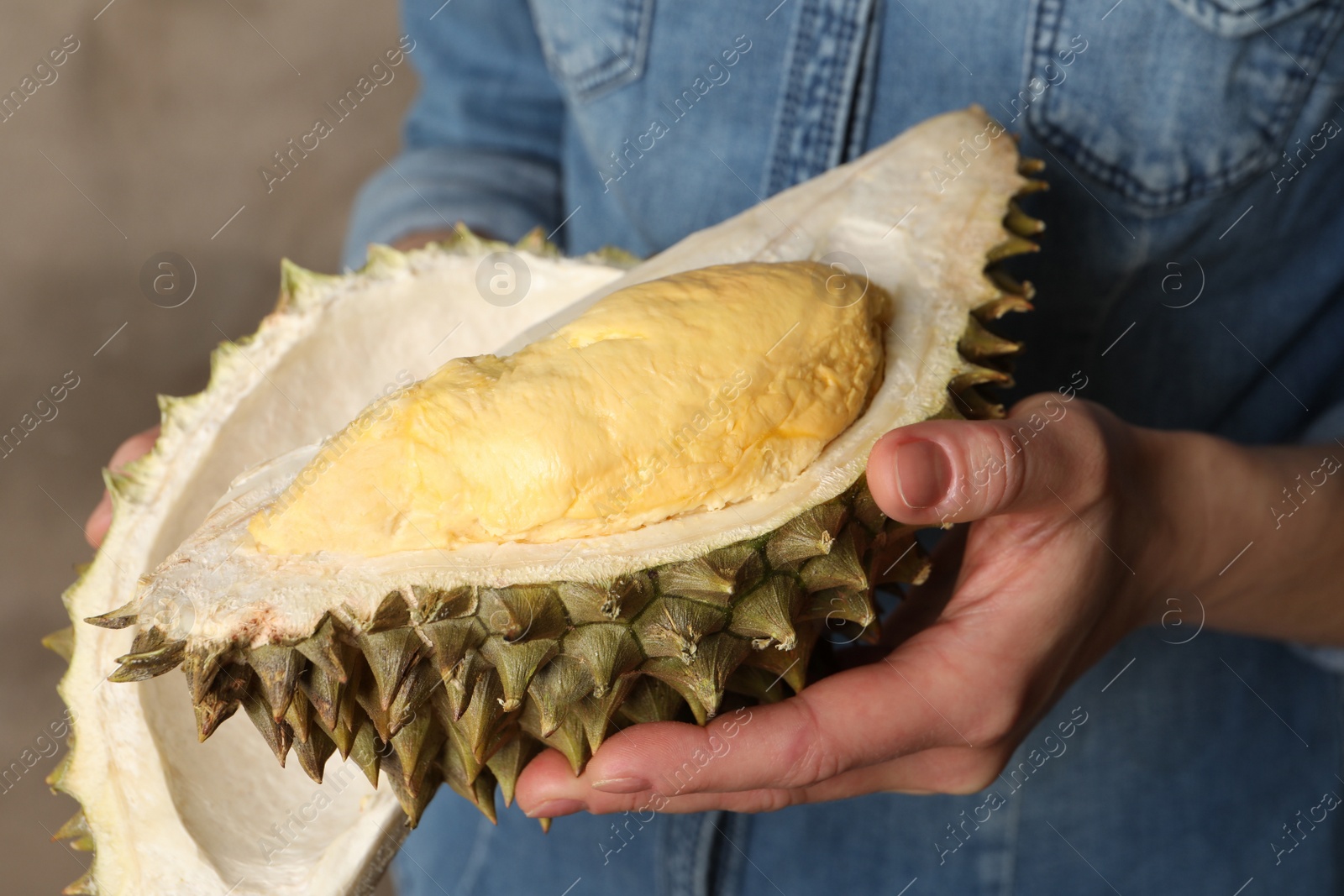 Photo of Woman holding ripe durian on grey background, closeup