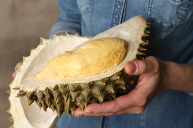 Photo of Woman holding ripe durian on grey background, closeup