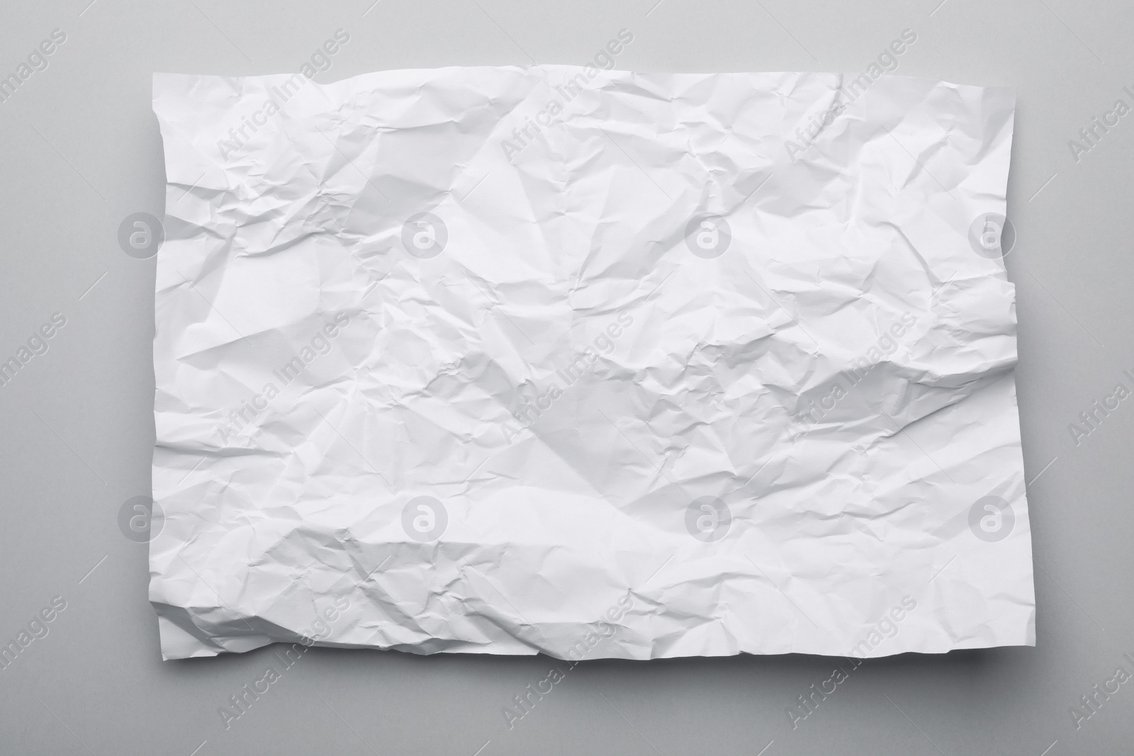 Photo of Sheet of crumpled paper on grey background, top view