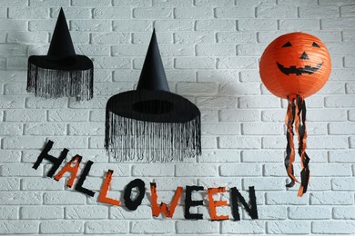 Word Halloween made of colorful letters and festive decor on brick wall
