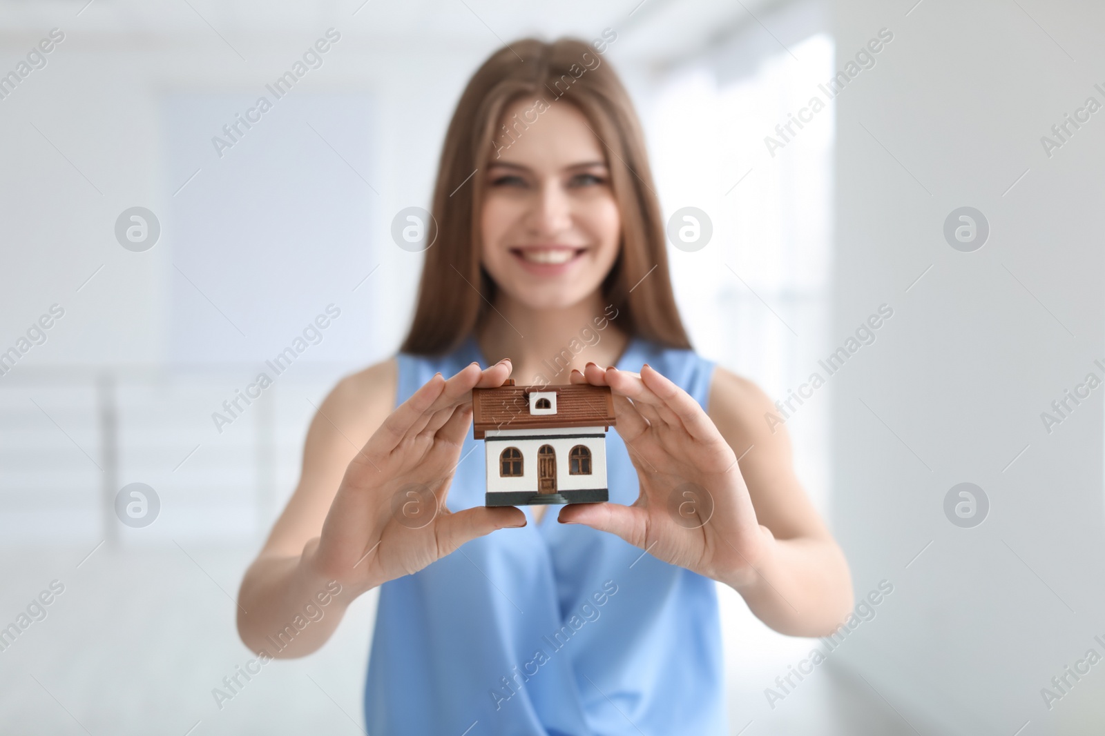 Photo of Beautiful real estate agent with house model indoors