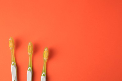 Photo of Toothbrushes on orange background, flat lay. Space for text