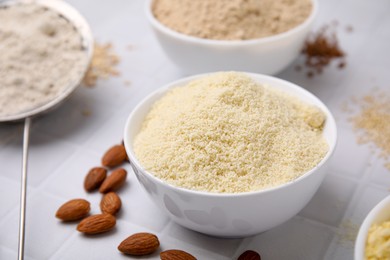 Photo of Bowls with different types of flour on tiled table, closeup