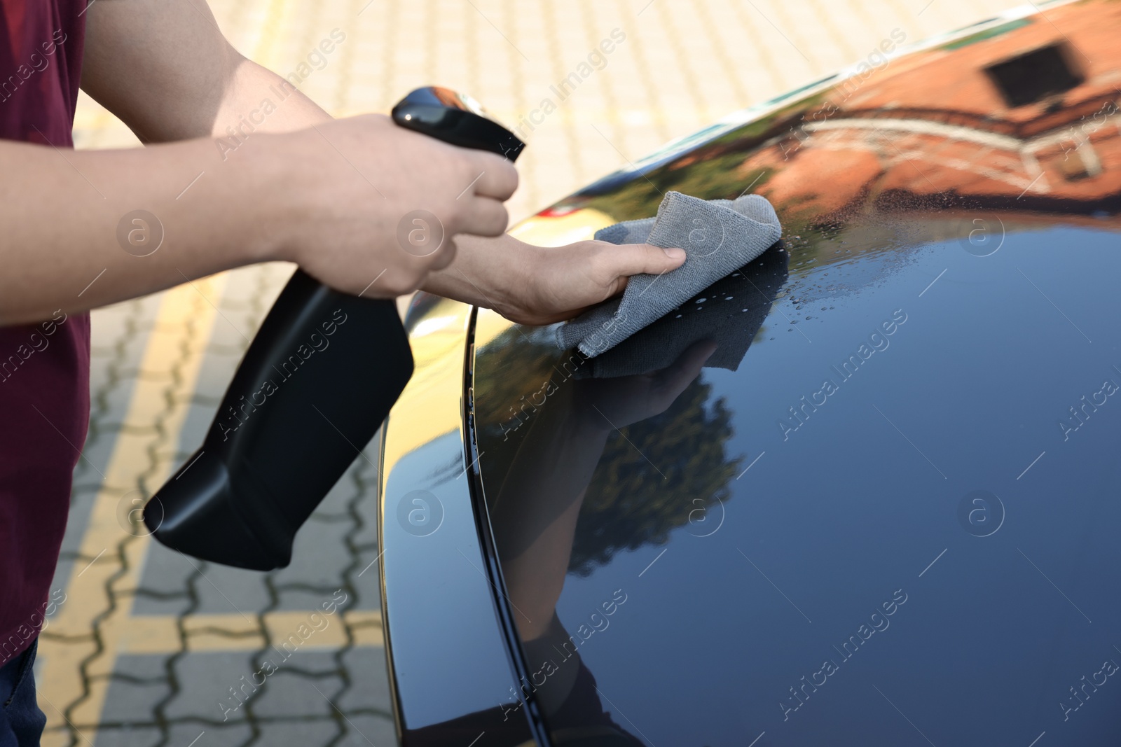 Photo of Man cleaning car hood outdoors, closeup view