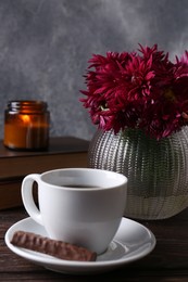 Photo of Beautiful pink chrysanthemum flowers and cup of aromatic tea with sweet chocolate cookie on wooden table