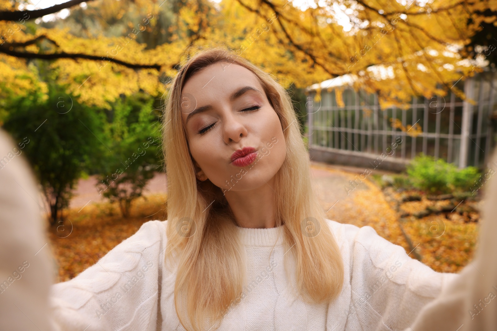 Photo of Portrait of cute woman taking selfie in autumn park