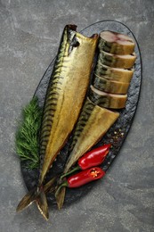 Delicious smoked mackerels with pepper, dill and spices on dark grey table, top view