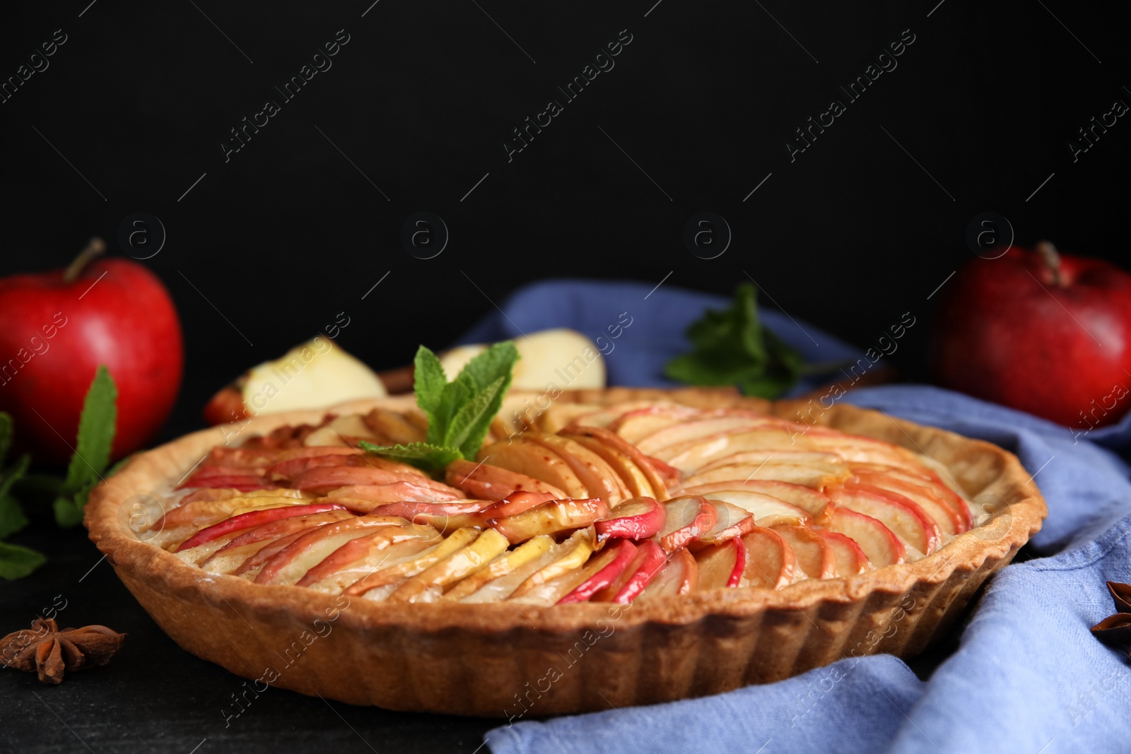 Photo of Delicious homemade apple tart with mint on black table