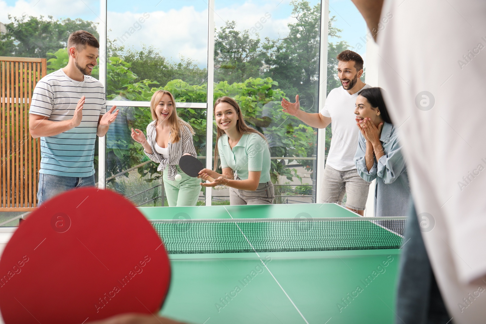 Photo of Happy friends playing ping pong together indoors