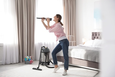 Happy woman having fun while cleaning bedroom