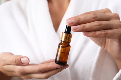 Photo of Woman with bottle of cosmetic serum, closeup