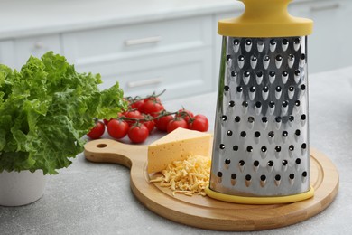 Photo of Grater, cheese and vegetables on table in kitchen