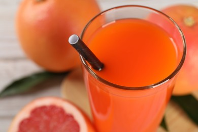 Photo of Tasty grapefruit juice in glass and fresh fruits on table, closeup. Space for text