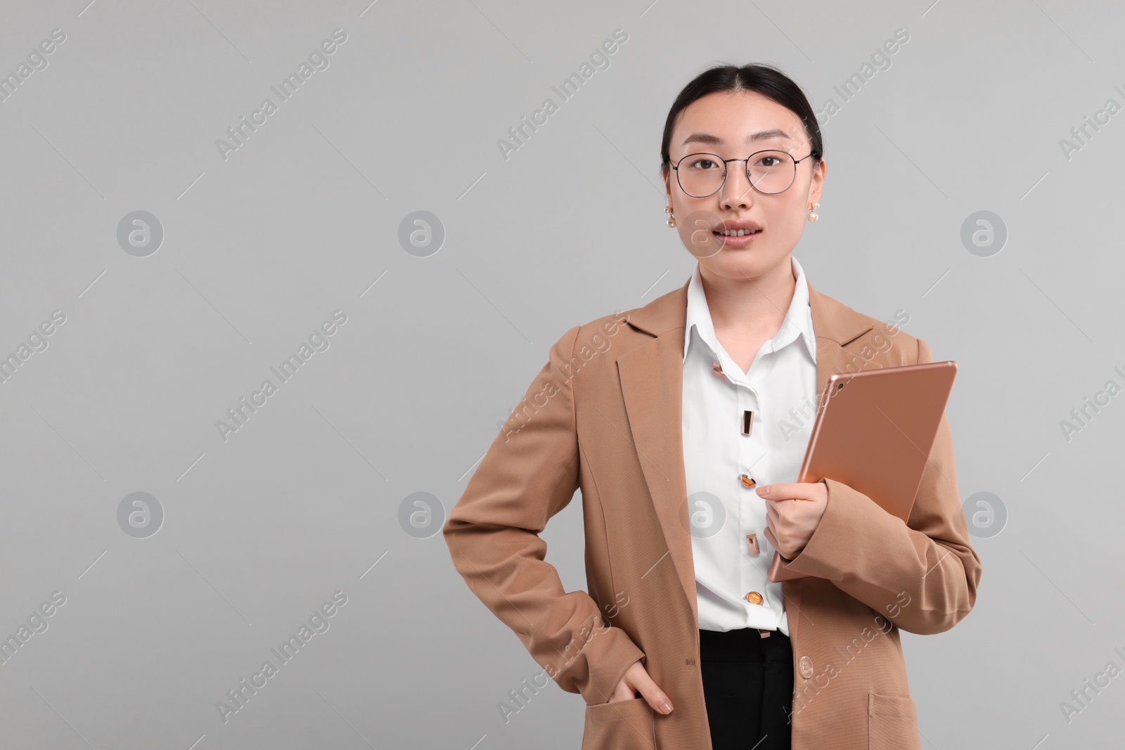 Photo of Portrait of beautiful businesswoman with tablet on grey background. Space for text