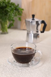 Delicious coffee in cup and moka pot on light textured table