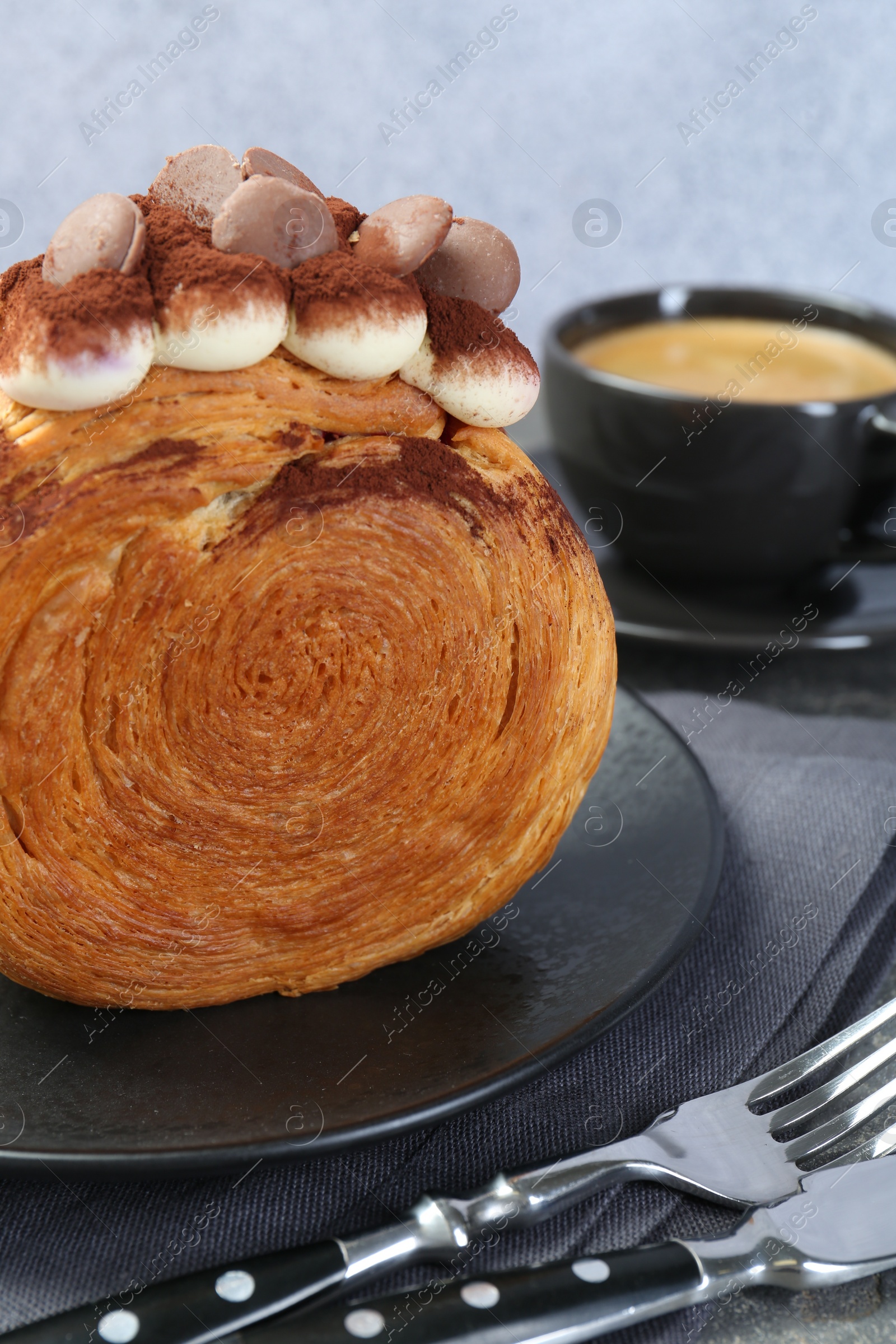 Photo of Round croissant with chocolate chips and cream served on table, closeup. Tasty puff pastry