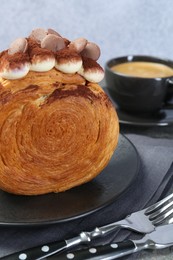 Round croissant with chocolate chips and cream served on table, closeup. Tasty puff pastry