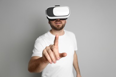 Photo of Man using virtual reality headset against light grey background, focus on hand