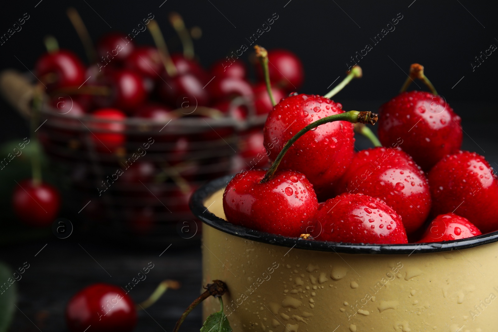 Photo of Metal mug with ripe sweet cherries on table, closeup. Space for text