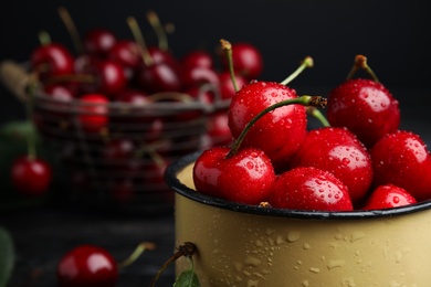 Photo of Metal mug with ripe sweet cherries on table, closeup. Space for text