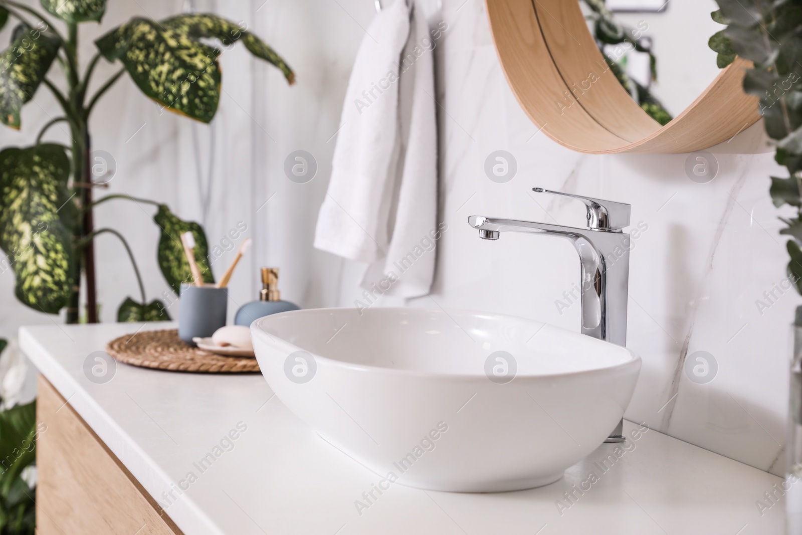 Photo of Stylish vessel sink and green plants in bathroom. Interior design element