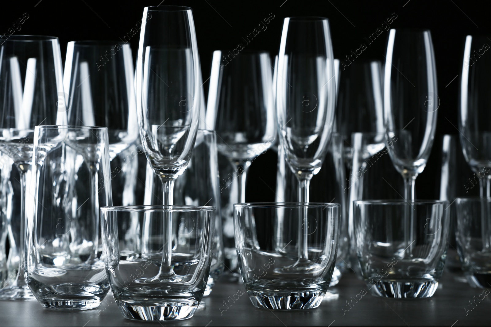 Photo of Set of empty glasses on table against black background