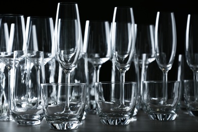 Photo of Set of empty glasses on table against black background