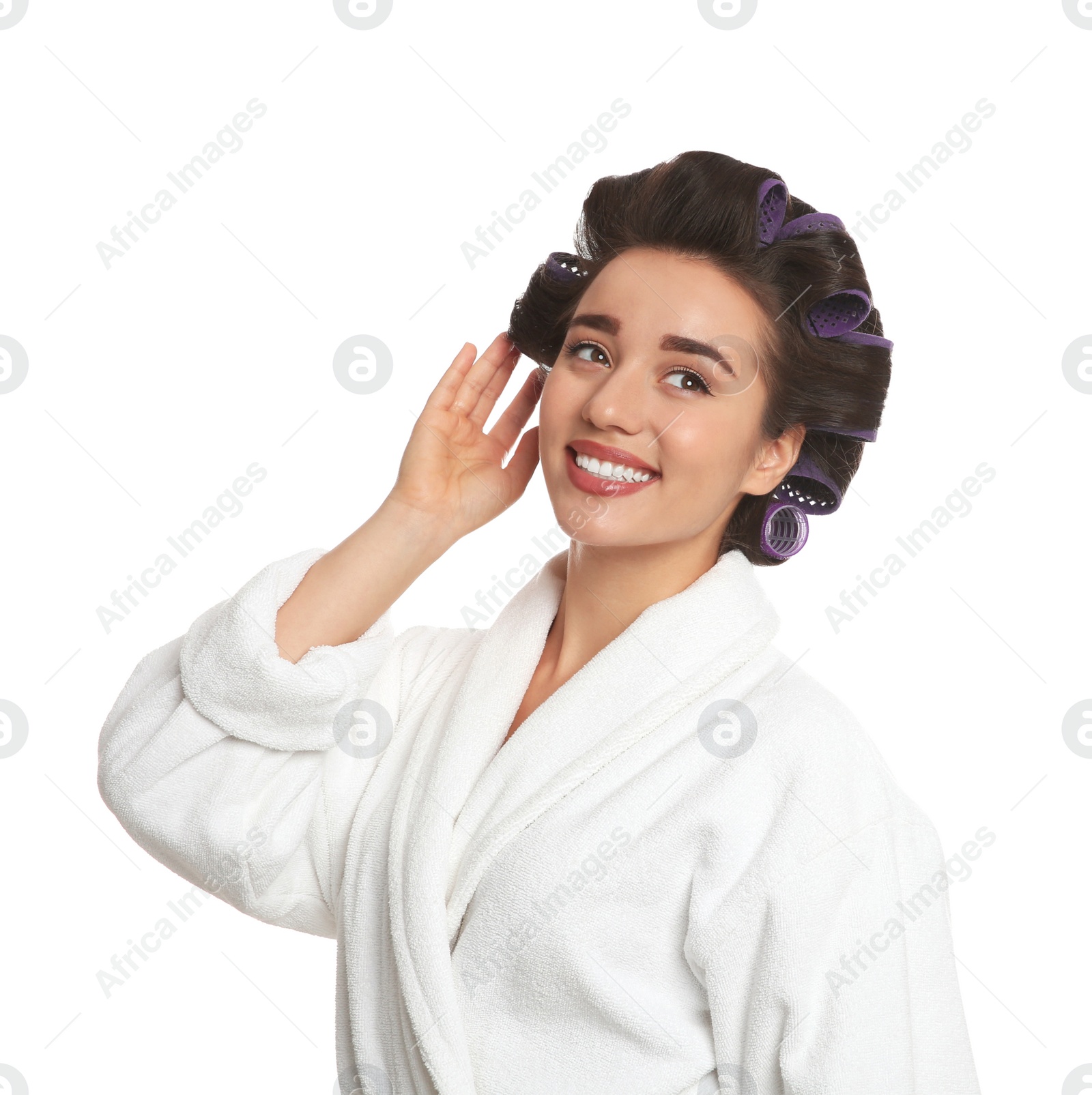 Photo of Happy young woman in bathrobe with hair curlers on white background