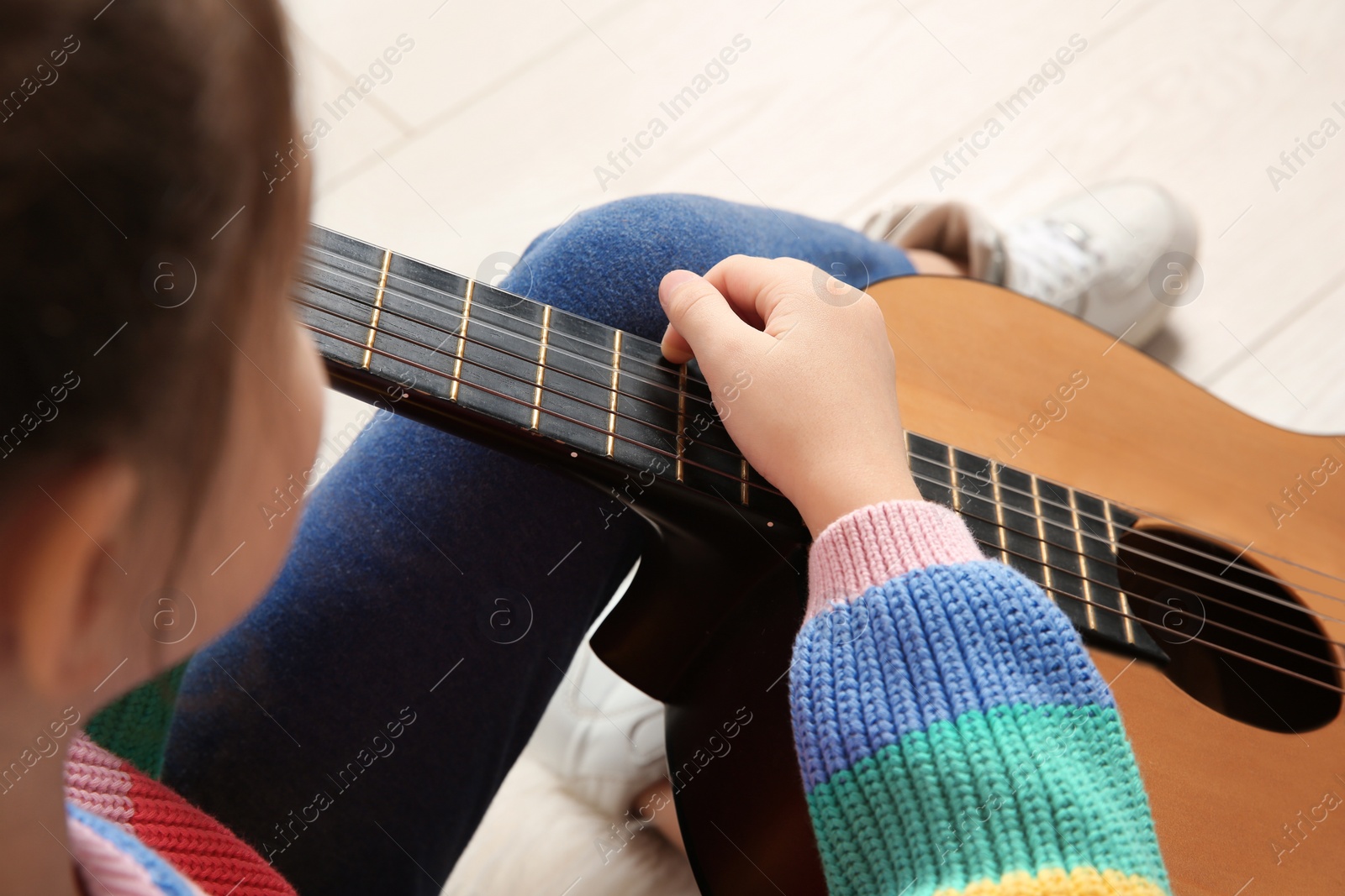 Photo of Little girl playing wooden guitar, closeup view