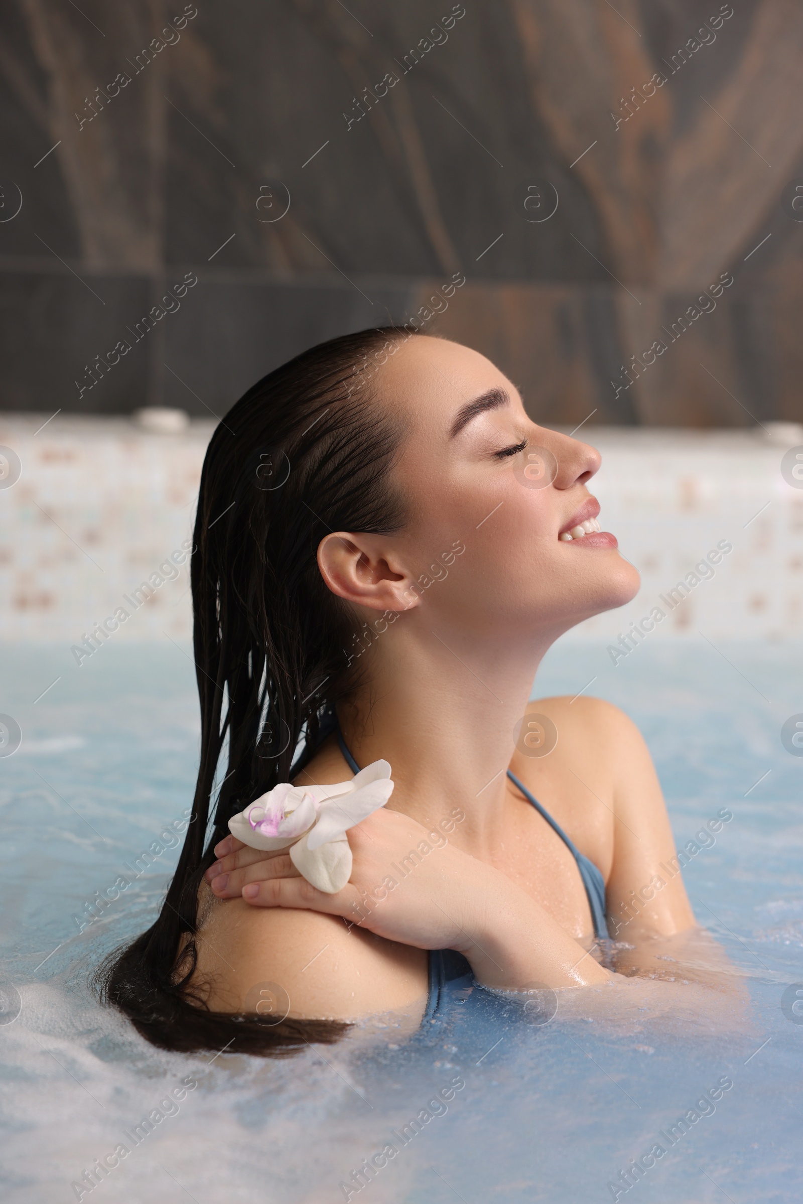 Photo of Beautiful woman with orchid flower relaxing in spa swimming pool