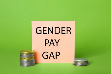 Photo of Gender pay gap. Paper note and stacked coins on light green background