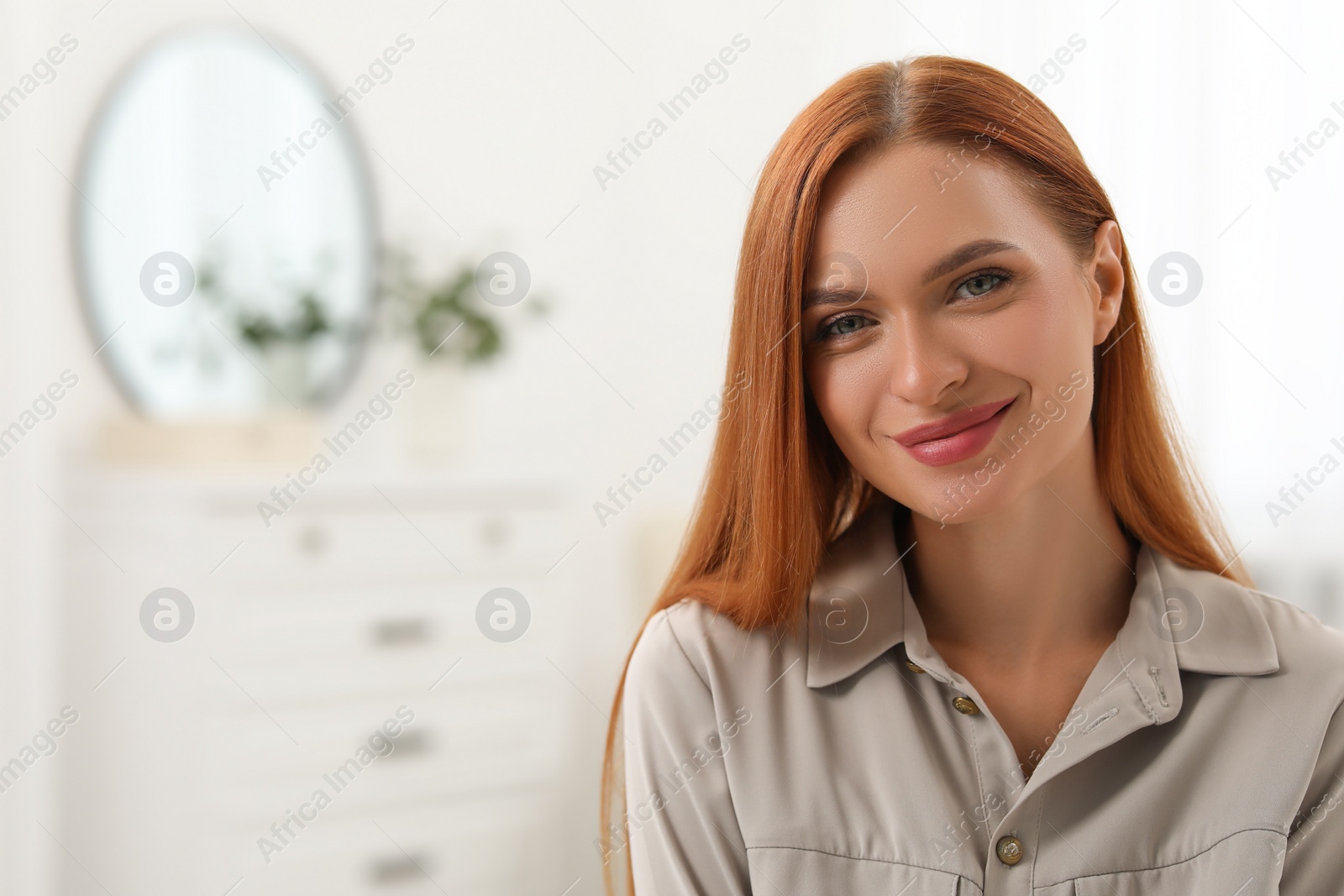 Photo of Portrait of beautiful young woman with red hair at home. Attractive happy lady looking into camera. Space for text
