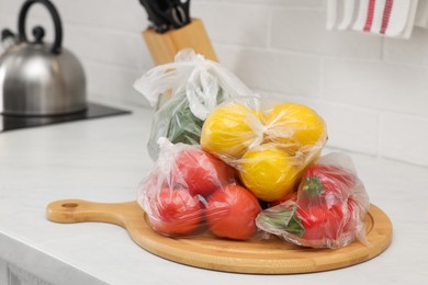 Plastic bags with different fresh products on white countertop in kitchen