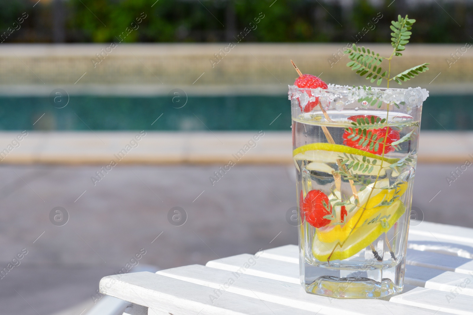 Photo of Delicious refreshing lemonade with raspberries on white wooden table outdoors, space for text