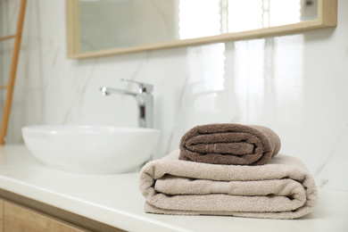 Stack of clean towels on bathroom countertop. Space for text