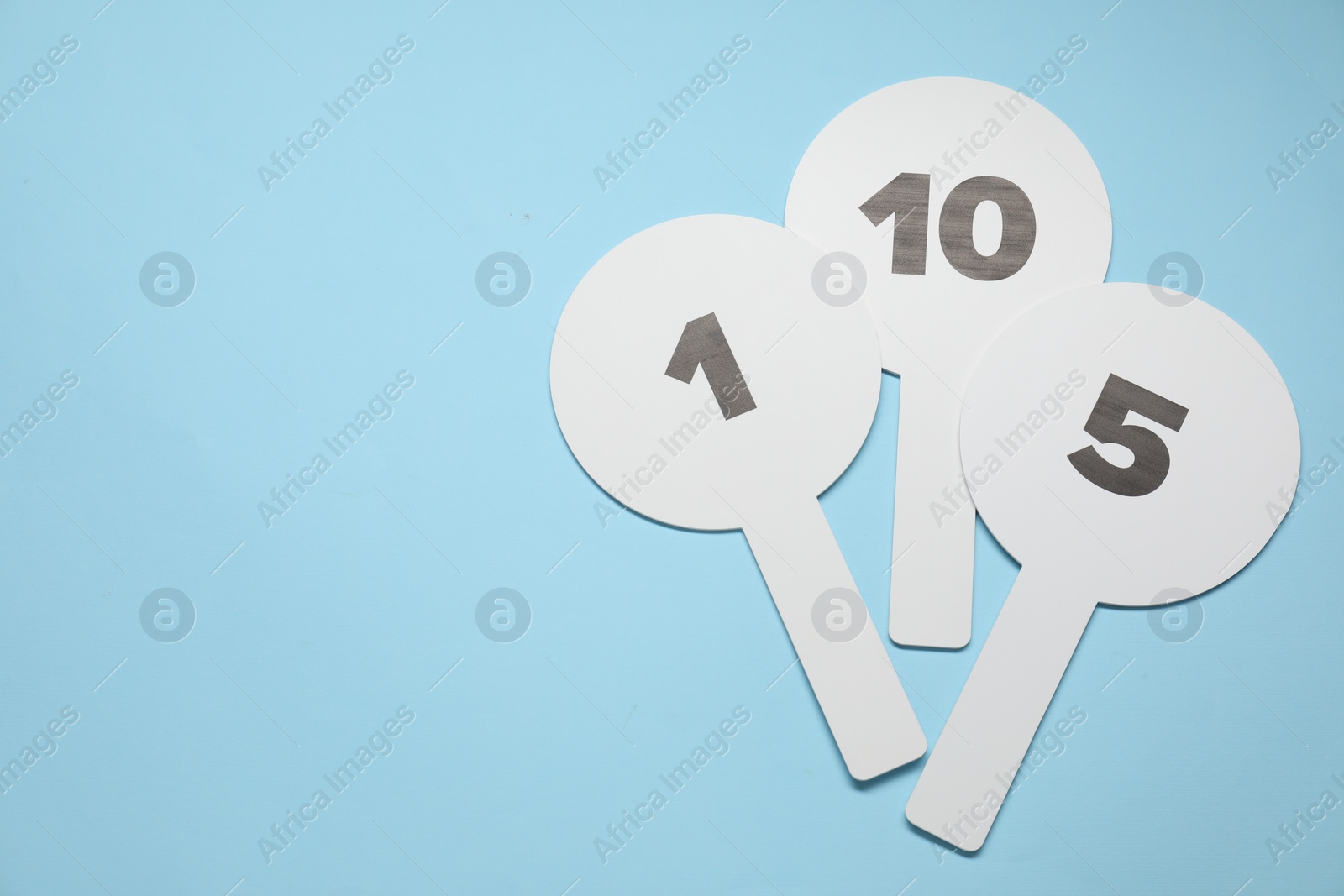 Photo of Auction paddles with numbers on light blue background, top view. Space for text