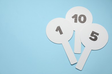 Photo of Auction paddles with numbers on light blue background, top view. Space for text