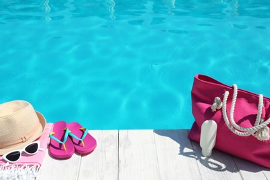 Photo of Beach accessories on wooden deck near swimming pool. Space for text